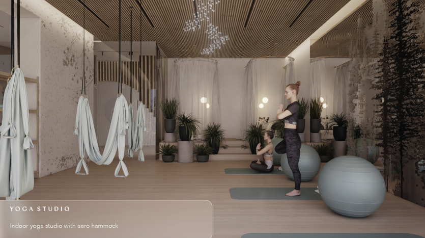 Un studio de yoga intérieur serein dans une luxueuse villa de Dubaï avec une femme pratiquant le yoga à côté d'un ballon d'exercice. Des hamacs aériens sont suspendus au plafond, entourés de plantes en pot et d'un éclairage chaleureux.