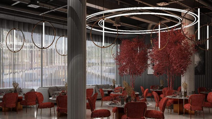 Intérieur de restaurant moderne avec d'élégantes chaises rouges, des tables circulaires et des luminaires circulaires distinctifs au-dessus. Les arbres rouges décoratifs ajoutent une touche unique au cadre spacieux et élégant, rappelant une villa à Dubaï.
