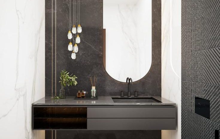 Une salle de bains moderne dans une villa de Dubaï comprenant un grand miroir ovale, un mur d'accent en marbre noir et une vanité flottante sombre avec des détails en laiton. Il y a des sols en marbre blanc et une chaise noire singulière et élégante