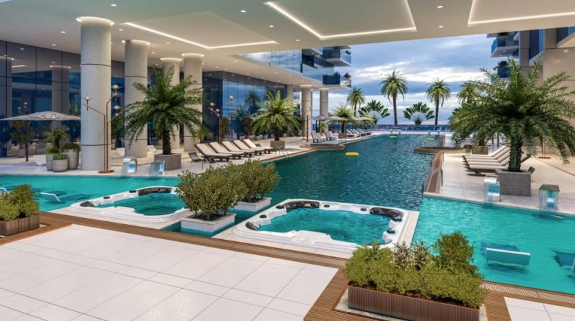 Espace piscine intérieure luxueuse dans un appartement de Dubaï comprenant plusieurs jacuzzis, chaises longues et palmiers, entourés de piliers modernes et offrant une vue imprenable sur l&#039;horizon.