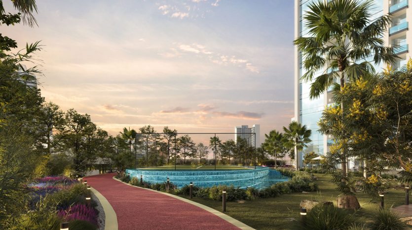 Un parc urbain serein au coucher du soleil avec un chemin rouge sinueux, une verdure luxuriante, des fleurs colorées et un bâtiment de verre moderne entouré de grands palmiers, illustrant le premier immobilier de Dubaï.