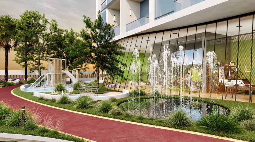 Immeuble résidentiel moderne à Dubaï avec une cour paysagée comprenant un sentier, des fontaines, une verdure luxuriante et une aire de jeux pour enfants, reflétant un espace de vie urbain bien entretenu.