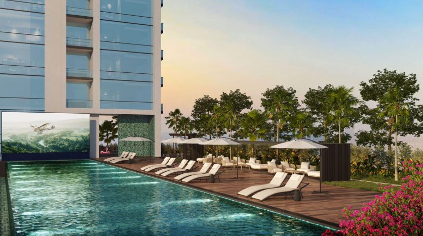 Rendu 3D d&#039;une luxueuse piscine à Dubaï au coucher du soleil avec des chaises longues et des parasols, flanquée d&#039;un immeuble moderne de grande hauteur d&#039;un côté et d&#039;une verdure luxuriante de l&#039;autre.