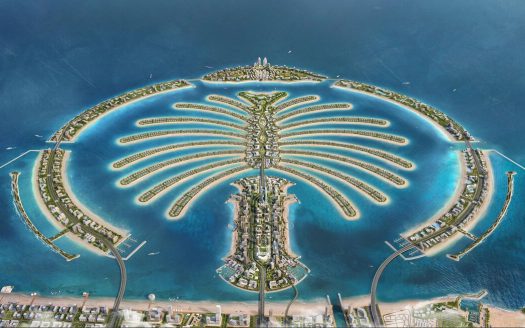 Vue aérienne de Palm Jumeirah à Dubaï, mettant en valeur sa forme unique de palmier avec des résidences et des hôtels luxueux le long d'îles en forme de frondes entourées d'eaux turquoise. Ce quartier renommé est parfait pour investir