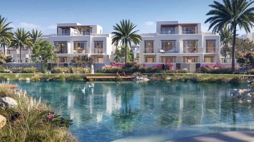 Villas résidentielles de luxe à Dubaï surplombant un lac artificiel tranquille aux eaux bleu clair. Des jardins luxuriants et des palmiers entourent la zone, renforçant la sérénité du cadre. Les cygnes nagent paisiblement
