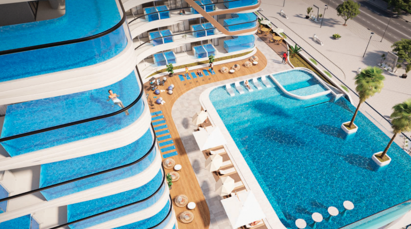 Vue aérienne d&#039;un hôtel de luxe doté de piscines bleues ondulées uniques à plusieurs niveaux reliées par des allées, entourées de salons et de palmiers à Dubaï.