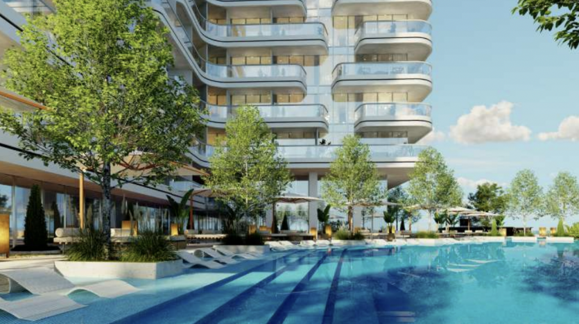 Des arbres luxuriants et des transats entourent une luxueuse piscine extérieure dans un complexe d&#039;appartements moderne à plusieurs niveaux à Dubaï, par une journée ensoleillée.