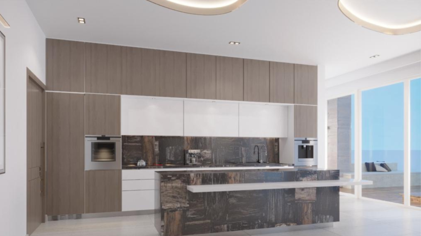 Une cuisine moderne avec des armoires en bois élégantes, des comptoirs blancs, des appareils électroménagers intégrés et un grand îlot de cuisine. Il y a une vue sur l&#039;océan à travers de grandes fenêtres en arrière-plan de cet appartement Dubaï