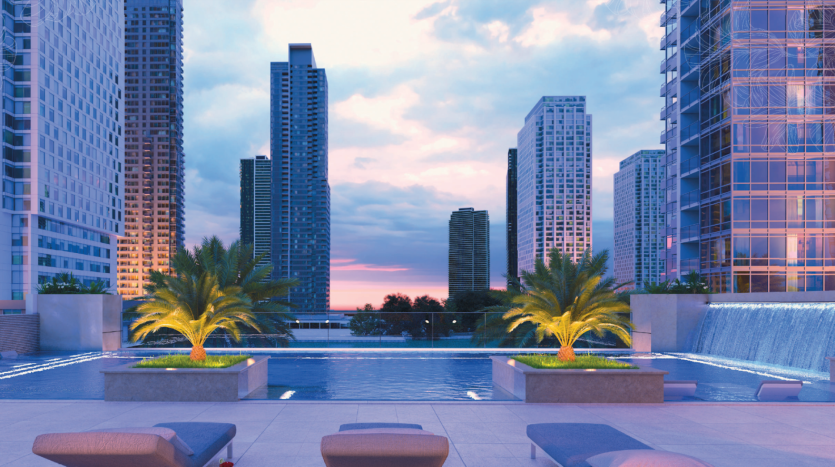 Piscine à débordement sur le toit surplombant un paysage urbain au coucher du soleil, encadrée par des immeubles de grande hauteur avec des fenêtres éclairées et des palmiers accentués par des lumières décoratives dans un appartement de premier ordre à Dubaï.