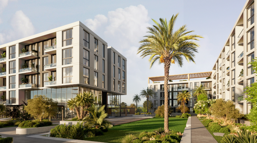Complexe résidentiel moderne composé de plusieurs bâtiments blancs dotés de balcons, entourés d&#039;une verdure soigneusement paysagée et d&#039;un chemin menant à un palmier central sous un ciel ensoleillé à Dubaï.