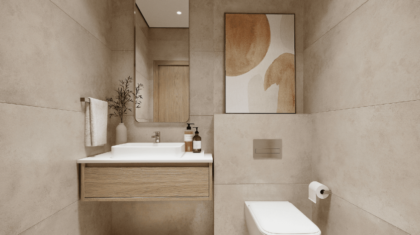 Intérieur de salle de bains de villa moderne à Dubaï avec carrelage beige neutre, comprenant une vanité en bois avec un comptoir blanc, un miroir mural, des œuvres d&#039;art et des toilettes blanches minimalistes. Une plante ajoute une touche naturelle.