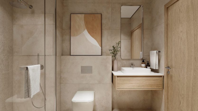 Une salle de bain moderne dans un appartement de Dubaï avec carrelage beige, douche en verre, armoires en bois et décoration minimaliste, avec un éclairage doux mettant en valeur une atmosphère épurée et sereine.