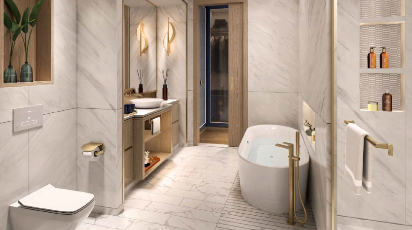 Une salle de bains luxueuse avec des murs et des sols en marbre dans une villa de Dubaï, comprenant une baignoire sur pied, des toilettes murales et un coin vasque avec lavabo. Des luminaires dorés et un éclairage élégant rehaussent l&#039;ambiance sereine.