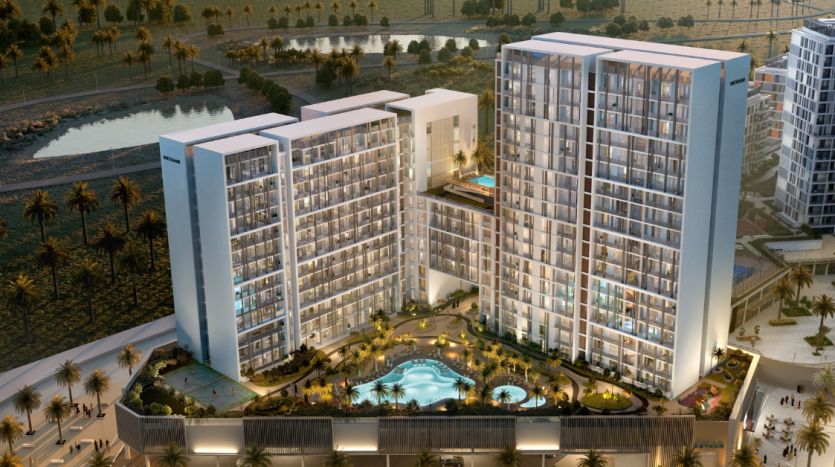 Vue aérienne d&#039;un complexe d&#039;appartements moderne de grande hauteur à Dubaï au crépuscule, avec des fenêtres éclairées, une piscine centrale, entourée de palmiers et d&#039;autres bâtiments.