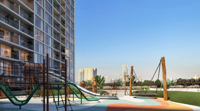 Une aire de jeux moderne avec des équipements colorés devant un immeuble résidentiel de grande hauteur, sous un ciel bleu clair, avec la villa Dubaï en arrière-plan.