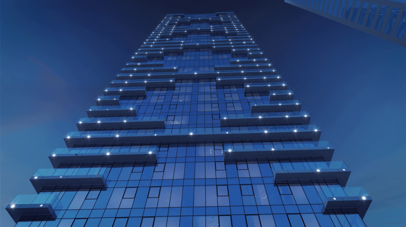Vue en contre-plongée d&#039;un gratte-ciel moderne éclairé par des lumières bleues sur un ciel sombre au crépuscule. Le bâtiment présente une conception décalée unique avec des fenêtres rectangulaires et carrées proéminentes, ce qui en fait une cible privilégiée pour