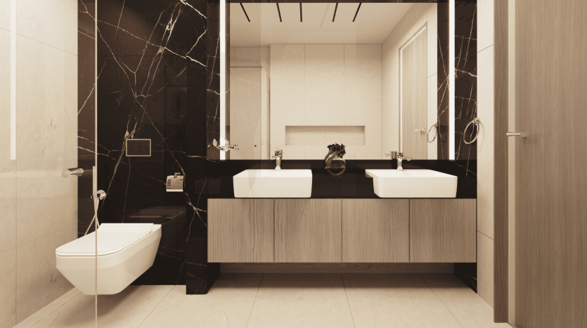 Intérieur de salle de bains moderne comprenant deux lavabos avec lavabos blancs sur une vanité en bois, de grands miroirs et des toilettes murales, contrastant avec le marbre foncé et les sols en bois clair dans un appartement de Dubaï.