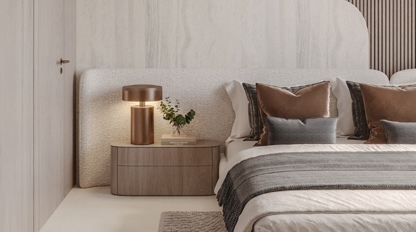 Chambre moderne dans une villa de Dubaï présentant une palette de couleurs neutres avec une tête de lit texturée, une table de nuit en bois, une lampe dorée et des oreillers décoratifs dans les tons marron et gris.