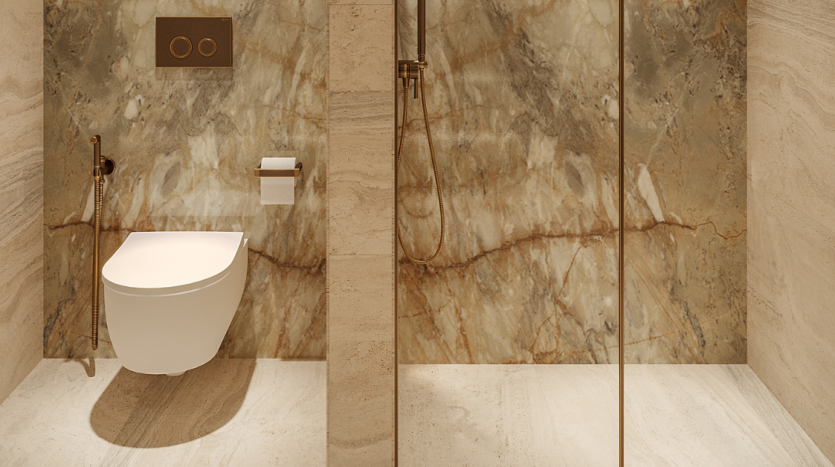 Une salle de bains moderne avec des murs et un sol en marbre, des toilettes autoportantes blanches, une cloison de douche en verre et des luminaires dorés dans une propriété immobilière d'élite de Dubaï.