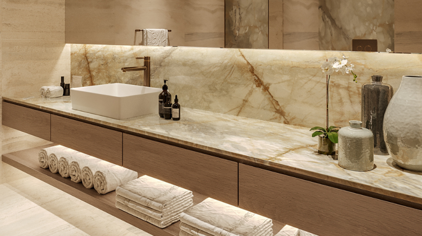 Intérieur de salle de bains élégant dans un appartement de Dubaï comprenant un comptoir en marbre avec un lavabo rectangulaire, un robinet en laiton et des serviettes blanches soigneusement disposées. Le décor comprend des vases et une orchidée, rehaussant le luxe,