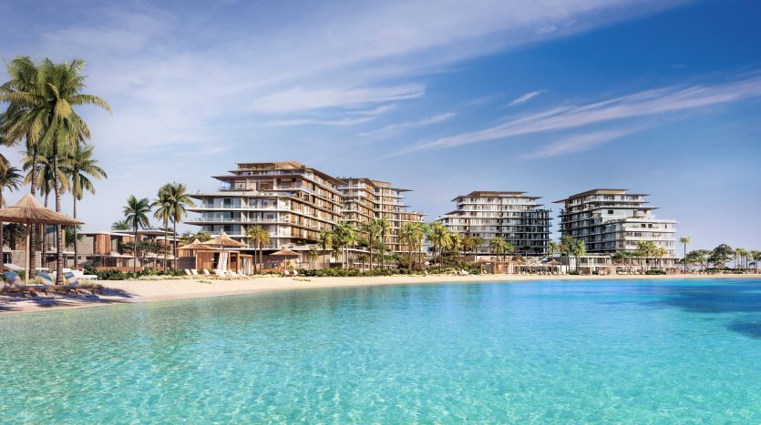 Complexe luxueux en bord de mer avec des bâtiments modernes à plusieurs étages, entouré de palmiers luxuriants, surplombant une grande piscine bleue sereine sous un ciel dégagé, idéal comme investissement immobilier à Dubaï.