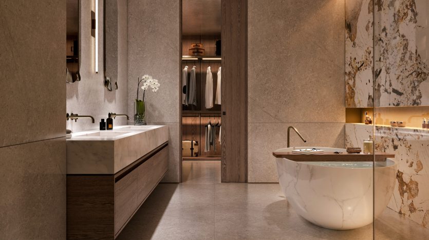 Une salle de bains luxueuse aux surfaces en marbre, avec une baignoire autoportante, une double vasque et un dressing visible en arrière-plan. Un éclairage doux et des bougies créent une ambiance sereine, parfaite pour un investissement exclusif