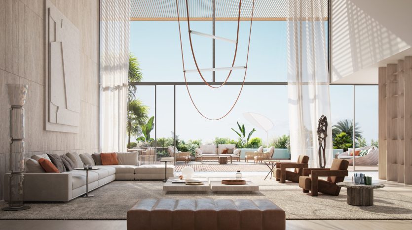 Un salon spacieux et ensoleillé dans un appartement Dubaï avec une décoration moderne, comprenant de grands canapés, des meubles en bois et une paroi vitrée coulissante donnant sur une terrasse. Une palette de couleurs subtiles et un art abstrait rehaussent