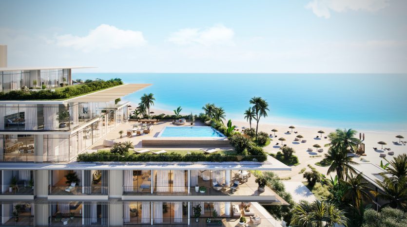 Une luxueuse villa en bord de mer à Dubaï avec des terrasses à plusieurs niveaux, une piscine à débordement et des rangées ordonnées de chaises longues sur une plage de sable fin, surplombant un vaste océan bleu sous un ciel clair.