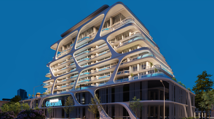 Un bâtiment futuriste à plusieurs étages au crépuscule à Dubaï, présentant une architecture curviligne avec des balcons lumineux et éclairés et un extérieur paysager.