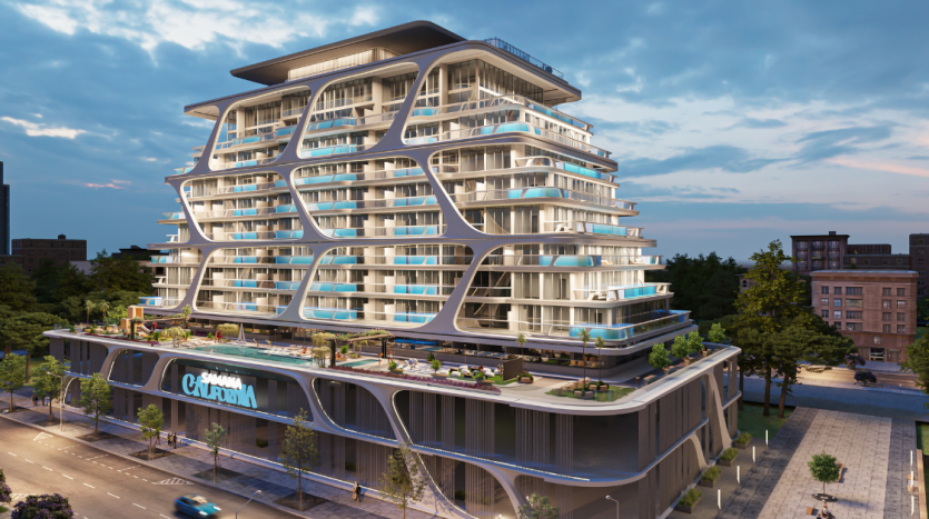 Un bâtiment moderne de plusieurs étages à Dubaï avec une architecture curviligne et de vastes balcons au crépuscule. Le niveau de la rue comprend une rangée de magasins de détail, une rue animée et de la verdure visible sur les terrasses