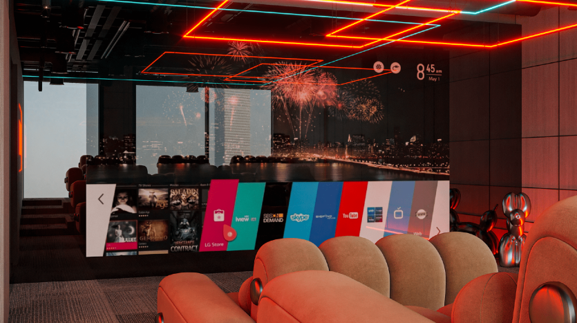 Une salle de cinéma maison moderne dans une villa à Dubaï avec des sièges moelleux, un grand écran projeté montrant des feux d&#039;artifice sur un paysage urbain et des néons vibrants au plafond. Divers logos de services de streaming sont affichés sur