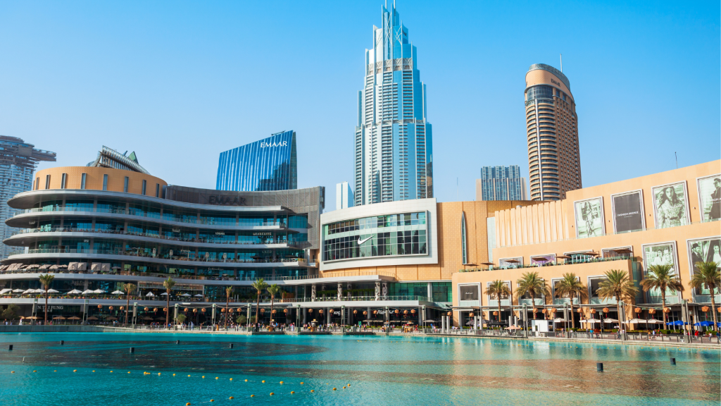 L&#039;architecture moderne et les bâtiments commerciaux bordent les rives d&#039;un lac urbain tranquille sous un ciel clair, incarnant le premier immobilier de Dubaï.