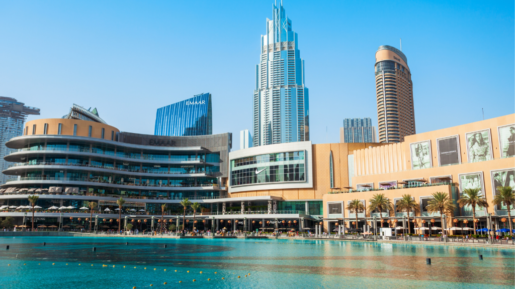 L'architecture moderne et les bâtiments commerciaux bordent les rives d'un lac urbain tranquille sous un ciel clair, incarnant le premier immobilier de Dubaï.