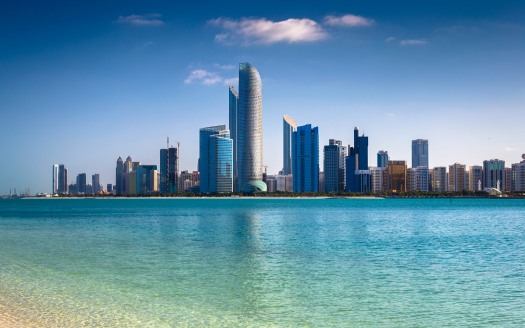 Une vue panoramique sur les toits de la ville moderne de Dubaï avec des gratte-ciel distinctifs au bord d'une mer bleue tranquille sous un ciel clair.