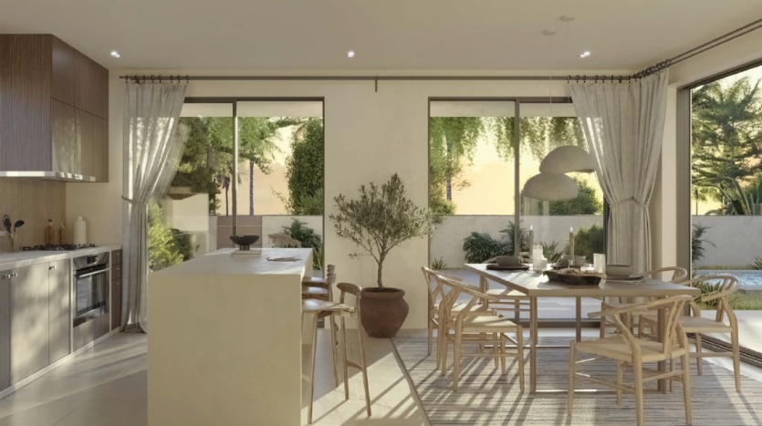 Cuisine ouverte moderne et coin repas avec lumière naturelle, meubles en bois, tons neutres et grandes fenêtres donnant sur un jardin, parfaits pour l&#039;immobilier Dubaï.