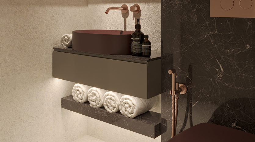 Un meuble-lavabo moderne dans une villa de Dubaï comprend un lavabo marron, des robinets en cuivre et des serviettes blanches décoratives exposées sur une étagère en marbre. Il présente un design minimaliste avec un éclairage tamisé.