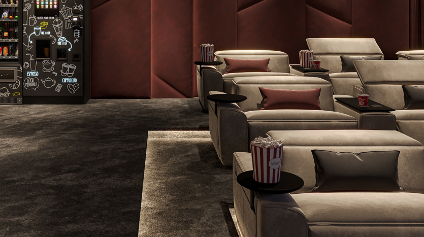 Salle de cinéma de luxe dans un appartement de Dubaï comprenant des rangées de fauteuils inclinables gris moelleux avec des coussins roses, des tables d&#039;appoint avec du pop-corn et un snack-bar faiblement éclairé en arrière-plan.