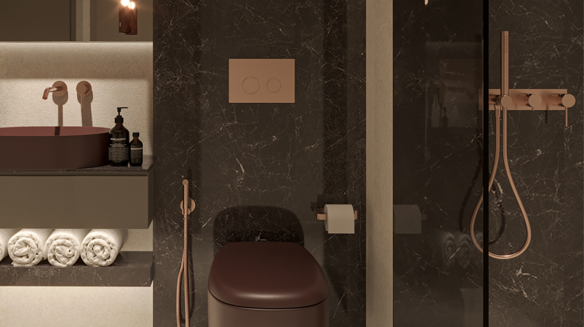 Une salle de bains moderne et luxueuse dans un appartement à Dubaï, dotée d&#039;un robinet, d&#039;un lavabo et d&#039;accessoires de douche en or rose, accentués par des murs en marbre foncé et une pile de serviettes blanches soigneusement pliées.