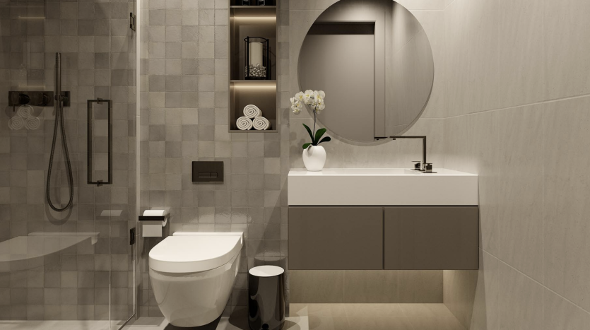 Intérieur de salle de bains moderne comprenant des toilettes murales, une vanité élégante avec un miroir rond et une douche à l'italienne. Les tons neutres et les étagères organisées rehaussent le design minimaliste de cet appartement de Dubaï.