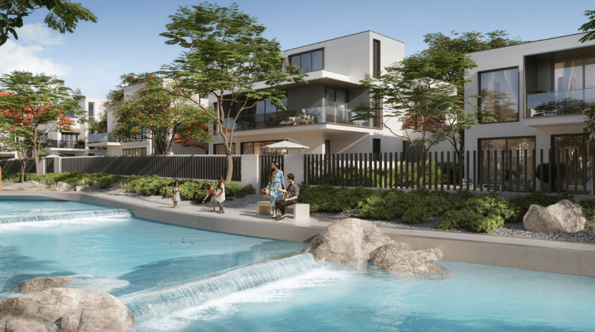 Quartier résidentiel moderne avec des personnes bénéficiant d&#039;une piscine commune, entouré de maisons élégantes et d&#039;un aménagement paysager luxuriant à Dubaï, avec des rochers et des plantes vibrantes.