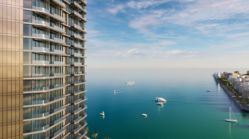 Vue panoramique depuis un immeuble de grande hauteur surplombant l&#039;océan à Dubaï, avec plusieurs bateaux sur l&#039;eau et un horizon de ville côtière sur la droite.