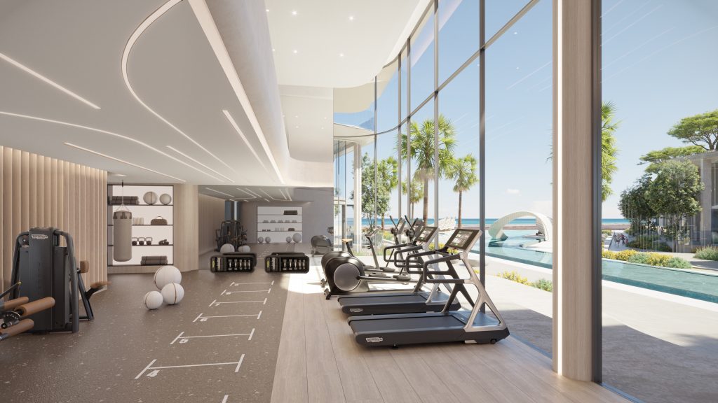 Une salle de sport moderne et spacieuse avec de grands murs de verre offrant une vue sur une plage tropicale et une piscine. Il est équipé de tapis roulants, de poids et d&#039;autres équipements de fitness, parfaits pour ceux qui investissent dans l&#039;immobilier.