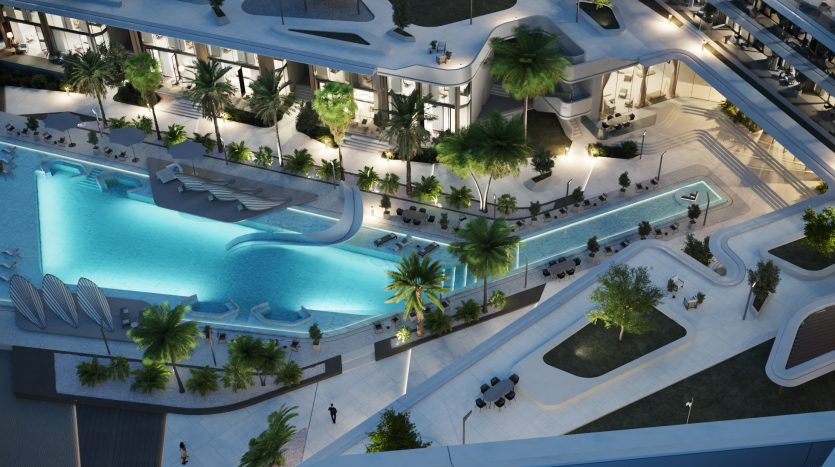 Vue aérienne d&#039;un complexe luxueux au crépuscule avec une grande piscine serpentine entourée de palmiers, des espaces de détente et des allées élégamment éclairées par un éclairage ambiant. Idéal pour investissement