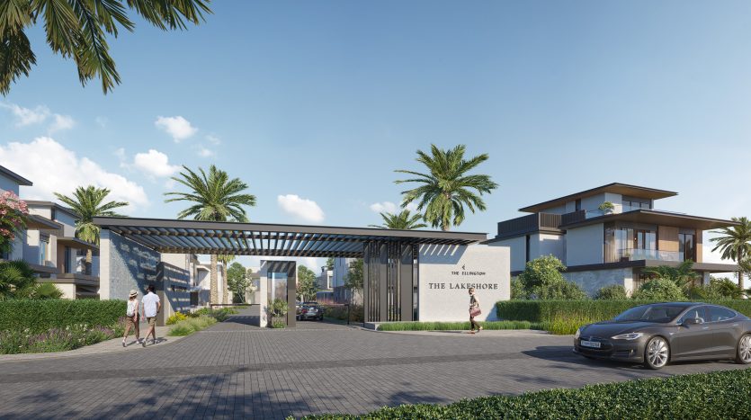 Une entrée de communauté résidentielle fermée moderne appelée &quot;The Lakeshore&quot; à Dubaï avec une voiture de luxe entrant, des passants et des villas de style contemporain avec un aménagement paysager luxuriant sous un ciel clair.