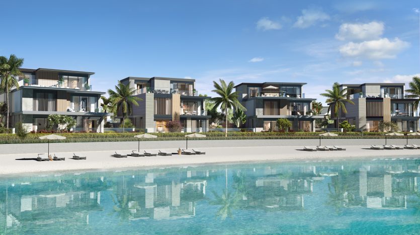 Complexe luxueux en bord de mer à Dubaï avec des villas modernes donnant sur une piscine tranquille aux eaux cristallines et des palmiers sous un ciel bleu clair. Des chaises longues sont disposées sur du sable blanc.