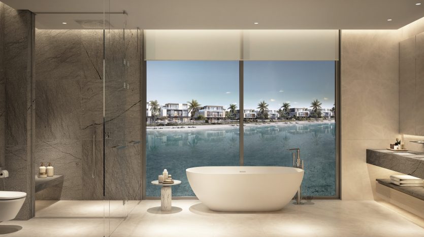 Intérieur de salle de bain luxueux avec baignoire autonome, douche en verre et double vasque dans une villa de Dubaï, doté de grandes fenêtres donnant sur une vue tranquille sur la plage.