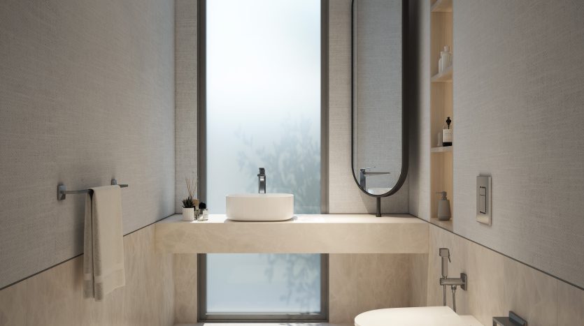Une salle de bains moderne dans une villa de Dubaï avec de grandes fenêtres laissant entrer la lumière naturelle, présentant un design minimaliste avec une vasque flottante, un lavabo rectangulaire, un miroir ovale et des toilettes élégantes. Carrelage aux tons clairs et serein