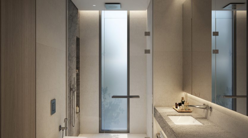 Salle de bain moderne dans un luxueux appartement de Dubaï comprenant une grande douche avec portes vitrées, un comptoir en pierre avec lavabo, des toilettes murales et un éclairage tamisé, offrant une ambiance sereine et luxueuse.