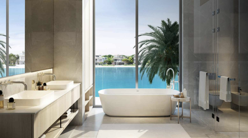 Une salle de bains luxueuse avec une baignoire autoportante, deux lavabos et une douche, donnant sur une piscine extérieure tranquille entourée de palmiers dans un appartement de Dubaï. De grandes baies vitrées offrent une vue sur un