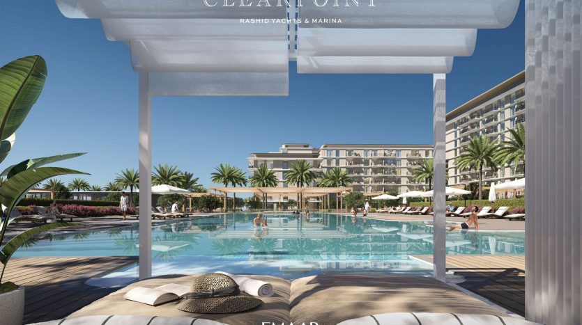 Vue depuis une luxueuse cabane au bord de la piscine avec un chapeau de paille sur le lit, donnant sur une grande piscine et une villa à Dubaï avec des palmiers sous un ciel bleu clair.